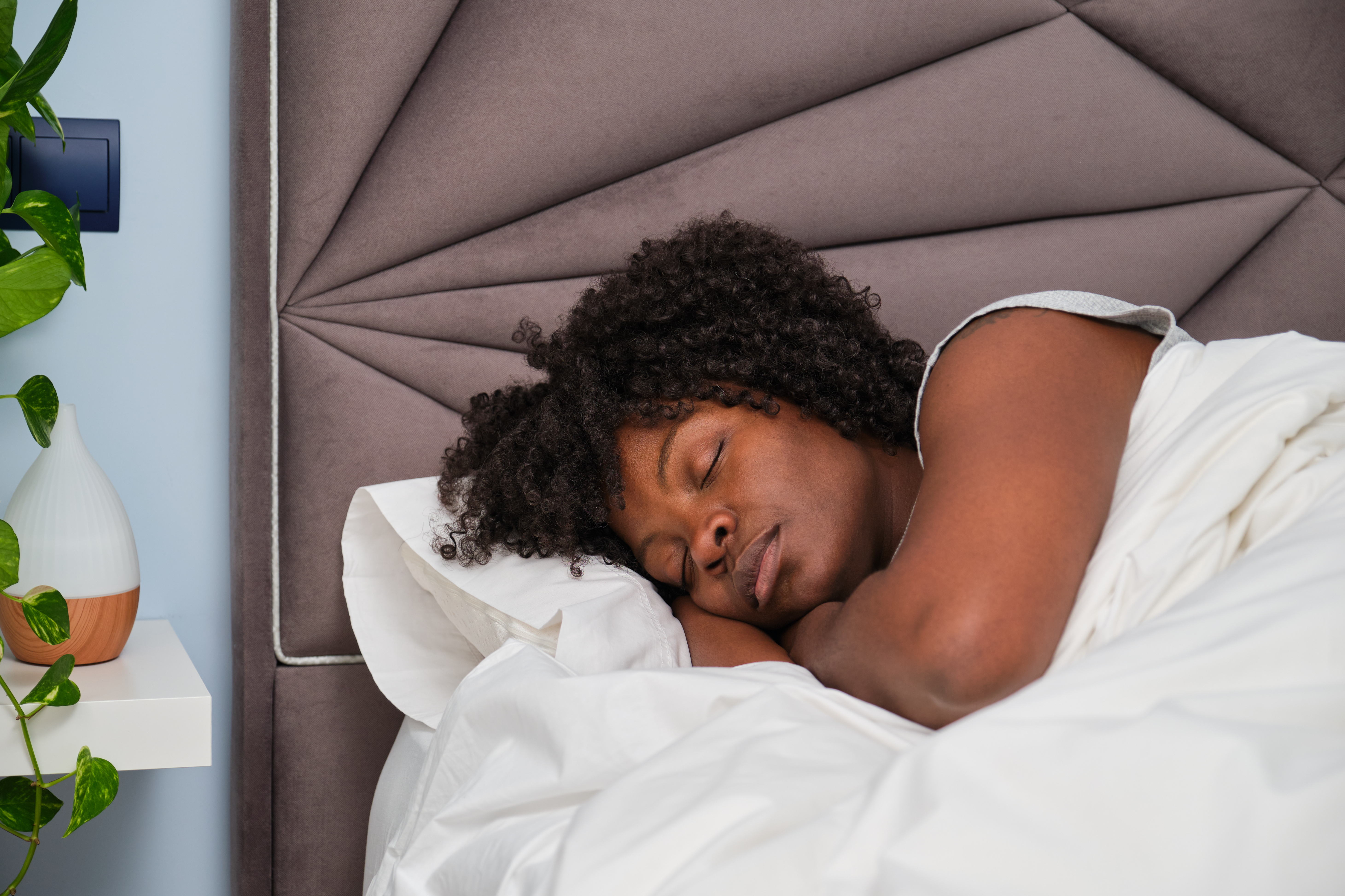 African young woman sleeping on white sheets in bed.
